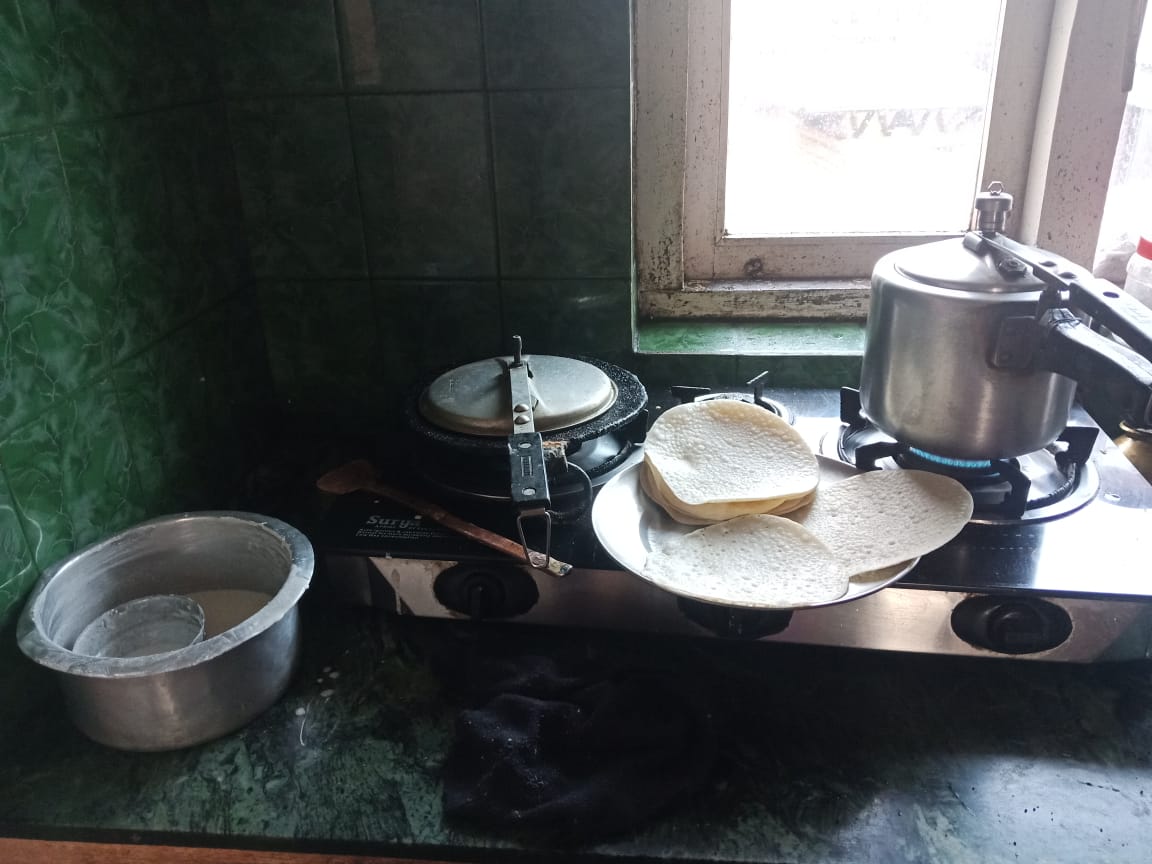 a small gas stove heating two cooking pots and a few tortillas