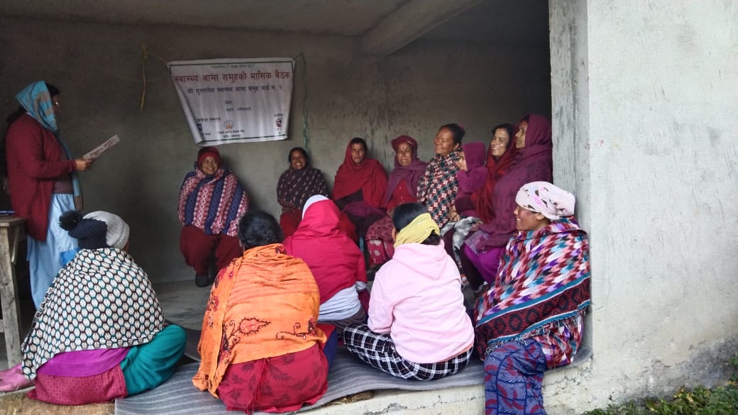 Approx. 14 women sitting together and attending a meeting.