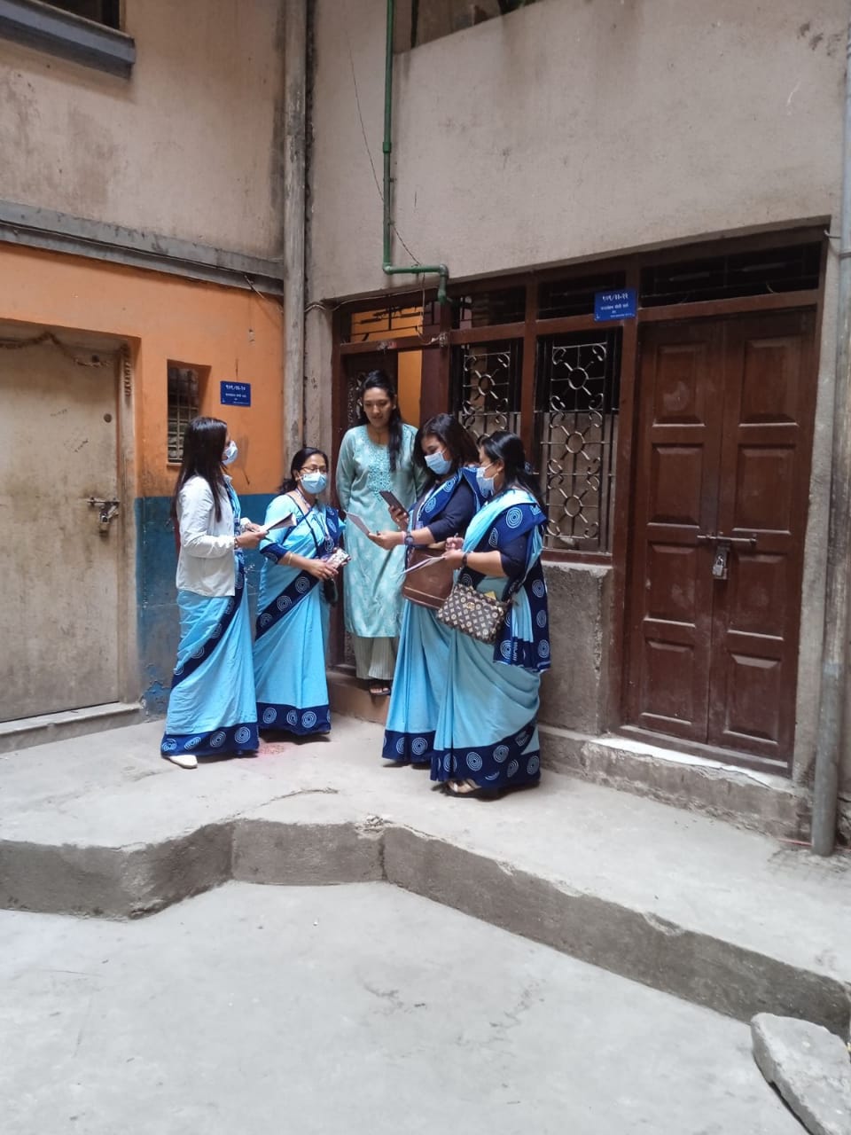 Five women in traditional dresses talking on a street corner.